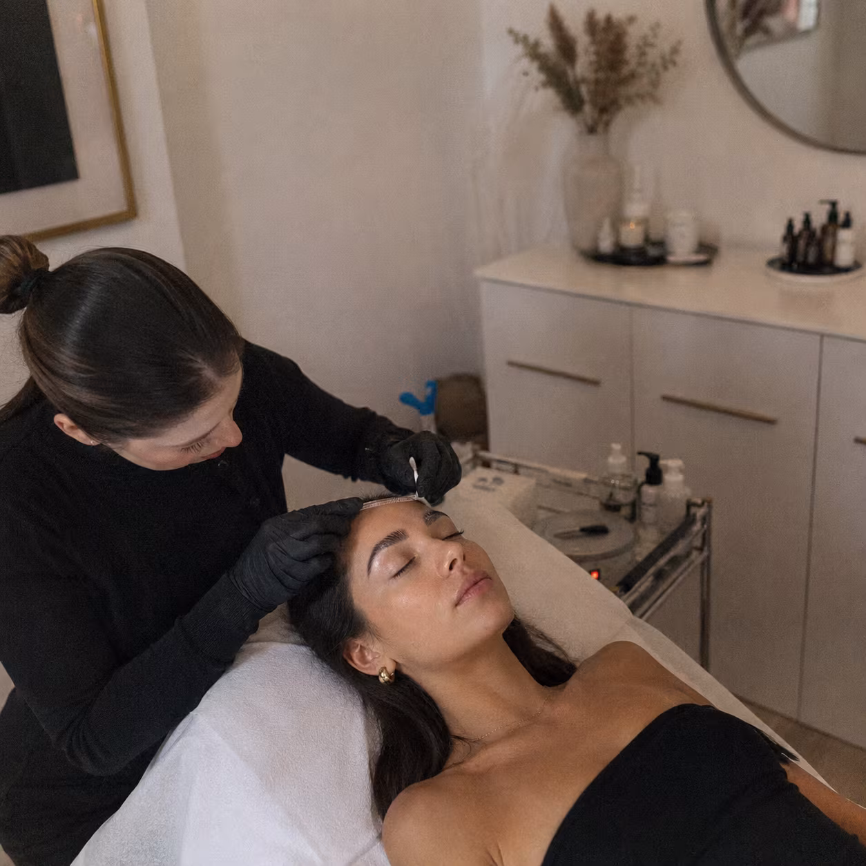 Brow specialist brushing a client’s eyebrows during a professional brow lamination treatment